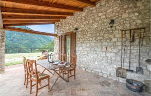 een tafel en stoelen op een patio met een stenen muur bij Lovely Home In Apecchio pu With Kitchen in Piobbico
