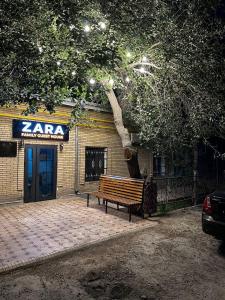 um banco de madeira sentado em frente a um edifício em ZARA Guest House em Bukhara
