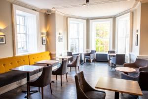 a restaurant with tables and chairs and windows at Arnos Manor Hotel in Bristol