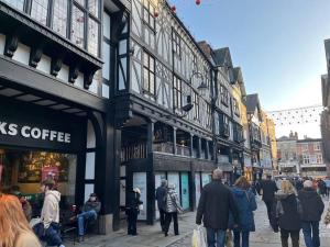 a group of people walking down a street with buildings at Studio On The Rows - Central City Centre in Chester