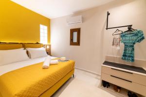 a bedroom with a yellow bed and a dresser at Bella Vasilica Luxury Apartments in Parga