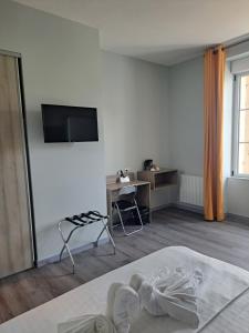 a bedroom with a bed and a desk and a television at Le petit Védaquais in Vaas