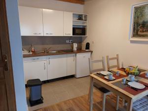 a kitchen with white cabinets and a wooden table at Gite de Moulin Maurt 1 in Xertigny