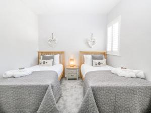 a bedroom with two beds and a table with a lamp at Sea La Vie in Benllech