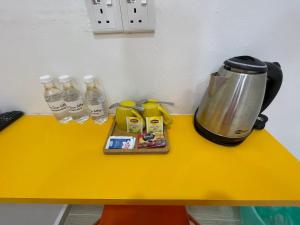 a table with a coffee pot and bottles of water at The Serai Cottage Transit Hotel in Kampong Gong Badak