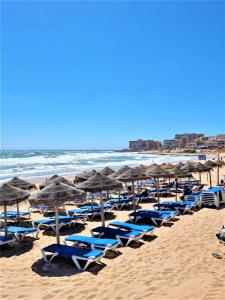 a bunch of chairs and umbrellas on a beach at Cabo Cervera primera linea apartamento de lujo in Torrevieja