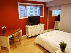 a bedroom with a bed and a desk and a tv at Bright Garden Suite by the Beach and UBC in Vancouver