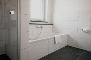 a white bathroom with a bath tub and a window at Ferienhaus am Mühlenweiher 4 in Leutkirch im Allgäu