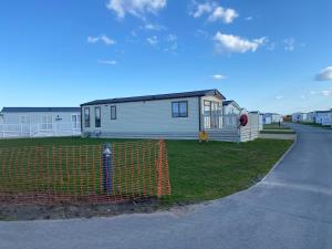 a house is behind an orange fence next to a street at Stunning 2 Bed Chalet in Silversands Lossiemouth in Lossiemouth