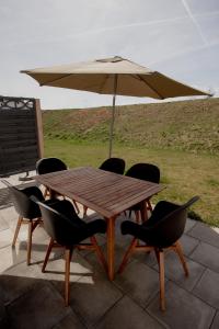 a wooden table with chairs and an umbrella at Ferienhaus am Mühlenweiher 5 in Leutkirch im Allgäu