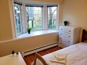 1 dormitorio con ventana, cama y vestidor en Bright Garden Suite by the Beach and UBC en Vancouver