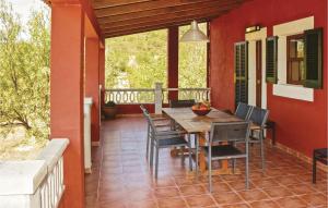 una casa con porche con mesa de madera y sillas en Awesome Home In Port Dalcdia With Kitchen, en Puerto de Alcudia