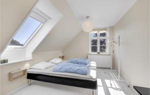 a bedroom with a bed in a white room with a window at Cozy Apartment In Gudhjem With Kitchen in Gudhjem