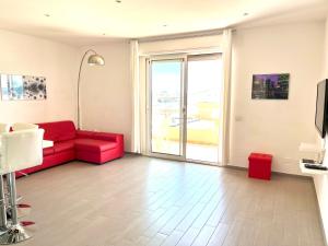 sala de estar con sofá rojo y ventana en Spinnaker Holidays, en Alghero