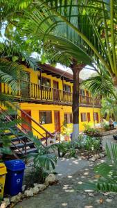 a yellow building with a palm tree in front of it at Rustic Beach Front Hotel Brasilito in Brasilito