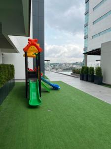 un parque infantil al lado de un edificio con césped verde en New luxury apartment with king - size bed Ceibos en Guayaquil