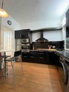 una cocina con armarios negros, mesa y sillas en O Cerrulo Apartamento céntrico Pontedeume, en Puentedeume