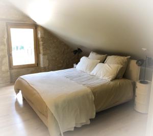 Schlafzimmer mit einem Bett mit weißer Bettwäsche und einem Fenster in der Unterkunft Maison Puchouaou Chambres d'Hôtes sur le chemin de Saint jacques de Compostelle in Montesquiou