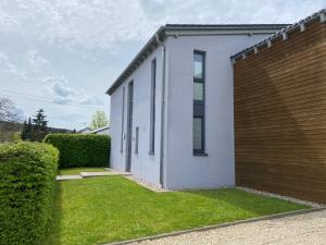 una casa blanca con una pared de madera junto a un patio en Moderne 70 qm Ferienwohnung in Waldrandlage, en Eppelborn