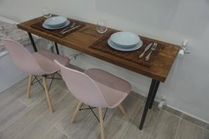 einem Holztisch mit zwei rosa Stühlen und Platten darauf in der Unterkunft Vasili's and Vasiliki's luxury apartment in Athen
