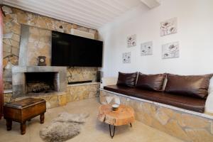a living room with a stone fireplace with a flat screen tv at Astarte Villas - The Pine Tree Villa with Pool in Makhairádhon