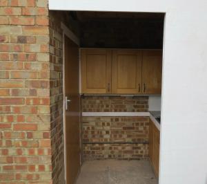una cocina vacía con armarios de madera y una pared de ladrillo en 31 Elwyn Snug en March