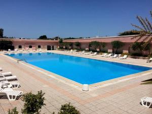 una gran piscina con sillas blancas y un edificio en Sea View Homes CB, en Baja Sardinia