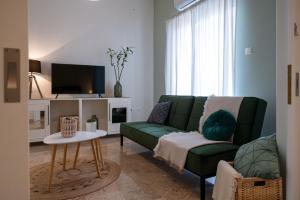 a living room with a green couch and a tv at Anesis with a Yard in Kalamata