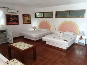 1 dormitorio con 2 camas y mesa en Hotel Catalina Beach Resort, en Zihuatanejo