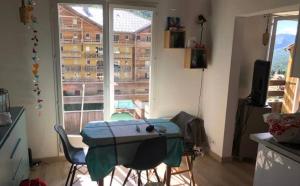 uma cozinha com mesa e cadeiras e uma janela em Appartement charmant - Allos em Allos