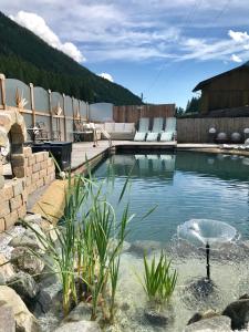 - une piscine avec des chaises dans l'eau dans l'établissement Apartments Schneiterhof - Der Frei-Raum, à Neustift im Stubaital