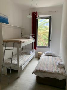 a bedroom with two bunk beds and a window at Hôtel Colombo- Porto Corse in Porto Ota