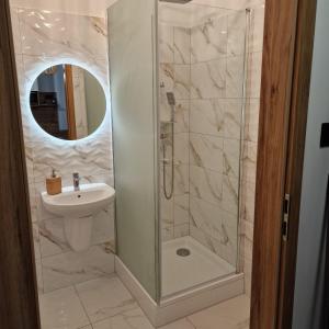 a bathroom with a shower with a sink and a mirror at Apartament Króla Sielaw - Mikołajki in Mikołajki