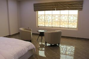 1 dormitorio con 1 cama, 2 sillas y ventana en Marina, en Sohar