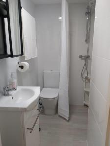 a white bathroom with a toilet and a sink at BeachFront House in Málaga