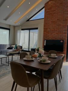 a dining room with a table and chairs and a tv at شاليه اوبل قاردن - OPAL GARDENS in Al Baha