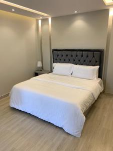 a bedroom with a large bed with white sheets and pillows at شاليه اوبل قاردن - OPAL GARDENS in Al Baha