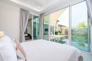 a bedroom with a large white bed and a pool at Peykaa Estate Pool Villa by HCR in Phuket Town