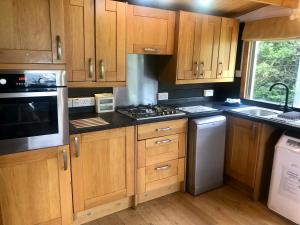 a kitchen with wooden cabinets and a stove top oven at Mulberry Cottage Farm in Wyboston