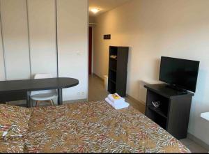 Cette chambre comprend un lit, une télévision et une table. dans l'établissement Studio - face de l’hôpital nord, à Saint-Priest-en-Jarez