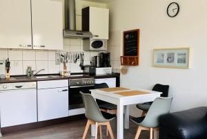 a kitchen with a table and chairs and a table and a counter at FeWo Seeluft - Hooksiel in Wangerland