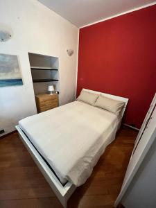 una camera con un letto bianco e una parete rossa di Bilocale Voltri Mare 4 posti a Genova