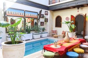 a patio with a pool and a table with plants at RIAD KECHMARA in Marrakech