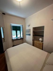 una camera da letto con un grande letto bianco e una finestra di Bilocale Voltri Mare 4 posti a Genova