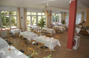 a restaurant with white tables and chairs and windows at Hotel Karlshof in Karlsdorf-Neuthard