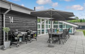 a patio with a grill and a table with chairs and an umbrella at Amazing Home In Ebeltoft With Wifi in Ebeltoft