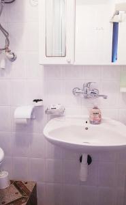 a white bathroom with a sink and a mirror at Apartmani Košutić in Stara Baška