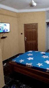 1 dormitorio con 1 cama y TV en la pared en STUDIO 2 Climatisé et Ventilateur Plafonnier et WIFI GRATUIT A 6 NUITEES DE RESERVATION en Lomé