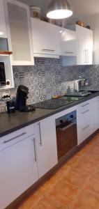 une cuisine avec des placards blancs et un comptoir noir dans l'établissement les romarins appartement climatisé, à La Seyne-sur-Mer