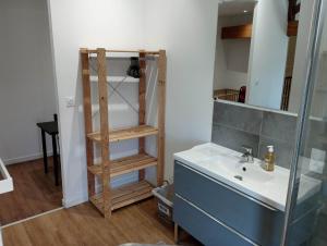 ein Badezimmer mit einem Waschbecken und einem Holzregal in der Unterkunft Chambre d'hôtes dans maison charentaise in Mortiers